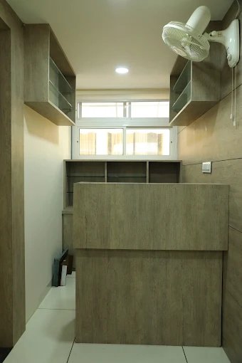 A clean and well-organized reception area with a wooden counter, shelving for storage, and a ceiling fan for comfort.