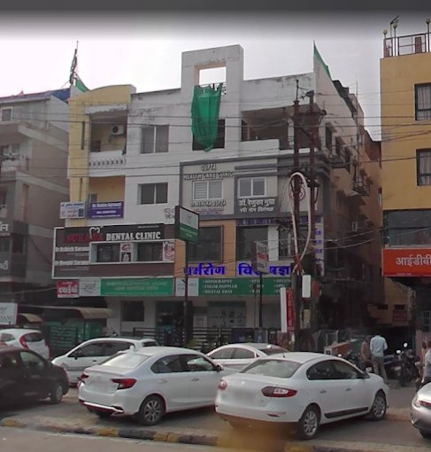The exterior of a bustling commercial building with various businesses, including a dental clinic, in a busy area.