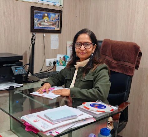 Dr. Renuka Gupta in her office, ready for work, with a well-organized desk and personal items that reflect her professional environment.